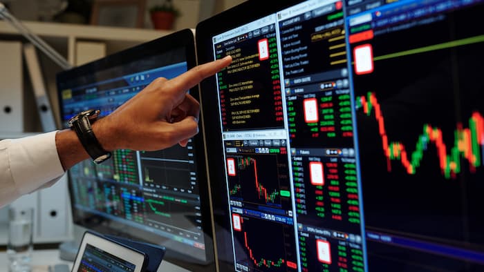 A finger pointing to a screen with stocks data