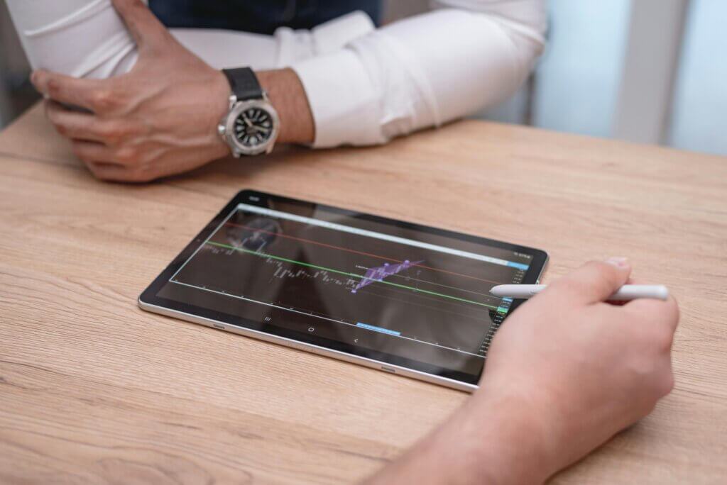 Black digital tablet on brown wooden table.