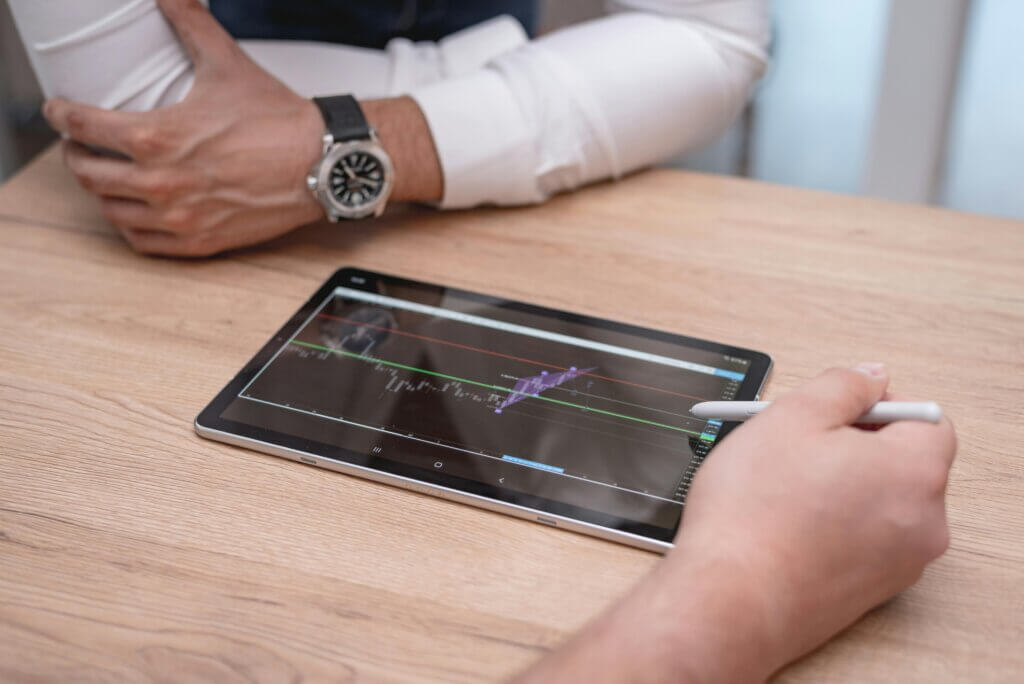 Black digital tablet on brown wooden table.