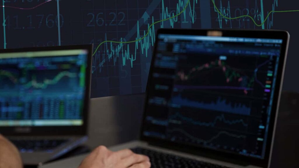 a trader in front of screens with trading charts